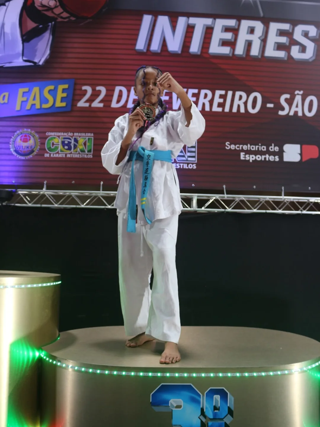 Aluna com medalha em pose de karatê